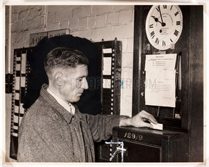 Weaver clocking on at the start of his shift  Wigan  November 1955.