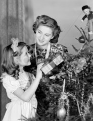 Woman and young girl by a Christmas tree  c 1950.