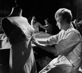 Female employee pins lingerie on to mannequin  1965.
