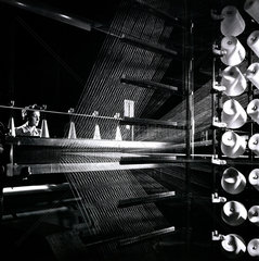 A female mill worker tends threads at carpet loom  Bolton 1956.