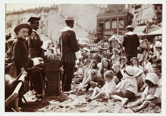 Crowd watching entertainers on a beach  Kent  c 1910.