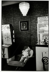 Young woman with a baby seated in amusement arcade  1969.