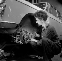 A young mechanic fits a disc brake to car  Smith Motors  Goodmayes  1960.