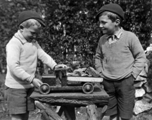 Two boys playing with a toy truck  c 1920s.