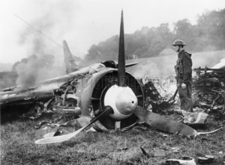 Soldier guards the burning remains of a Junkers 88  4 October 1940.