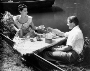 Couple having tea by a riverbank  1940s.