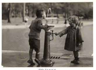Two children at a drinking fountain  c 1910.