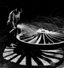 Sparks fly as man grinds locomotive wheel at Darlaston foundry  1953.