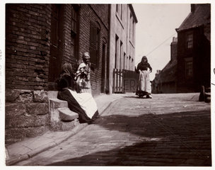 Women talking on a doorstep  c 1900.