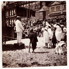 Crowd watching a beach entertainer  c 1905.