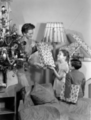 Woman giving Christmas presents to children  c 1948.