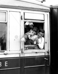 Schoolboys waving through the window of the train  June 1955.
