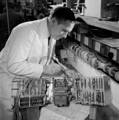 Electronic engineer solders a section of a data transmission item  MEL  1964.