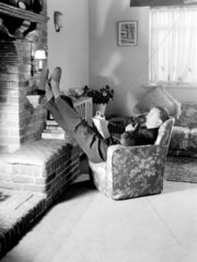 Man reading a book by the fire  c 1950.