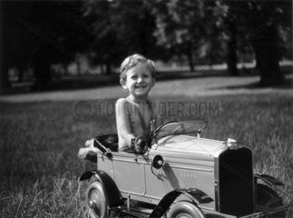 Little boy sitting in a toy car in the park