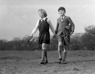 Boy and a girl wearing their school uniforms walking across a field  1948