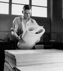 A young man folds new paper from imperial sheets at Star Paper  1959.
