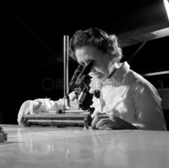 Female inspector uses microscope to check semi-conductors. GEC  1960.