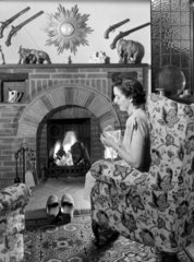 Woman knitting by the fire  c 1950.