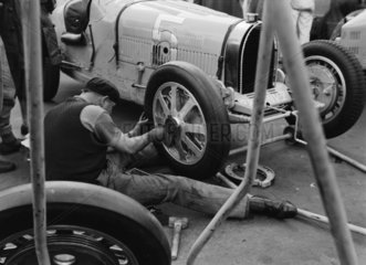 Robert Aumaitre working on Bugatti 1500 racing car wheel  Berlin  1933.