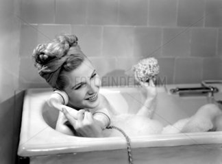 Woman on the phone in the bath  c 1950s.
