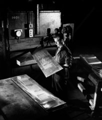 A worker inspects embossed aluminium sheets at press  Alcan  1961.