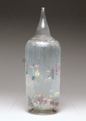 Large glass bottle containing glass amulets  French  c 1870-1920.