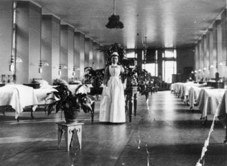 Nurse posing for camera in a hospital ward  c 1900s.