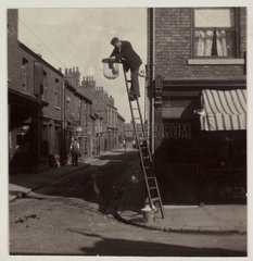 Man cleaning a gas street light  c 1905.