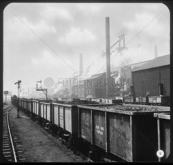 Train of iron ore tipplers at an industrial site.