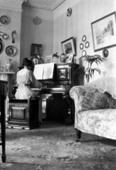 Woman playing the piano in an Edwardian dra