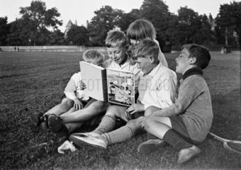 Five children sitting in the park reading a 'Bobby Bear's' annual  c 1930s.