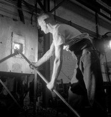 A foundry man with steel tube in small furnace  Talbot Stead Tubes  1948.