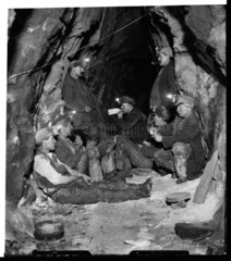 Tin miners taking lunch underground  1933.