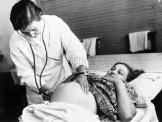 Doctor examining a pregnant woman  c 1950s.
