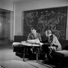 Two Gestetner managers in office discussion in front of a world map  1957.