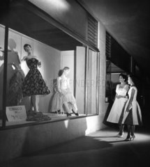 Two women looking at fashion display at night  Georgetown  Guyana  1958.