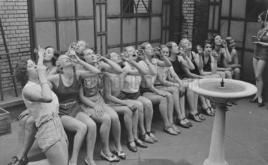 Dancers drinking from a water fountain  c 1930s.