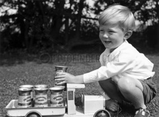 Small boy playing with a toy milk truck  c