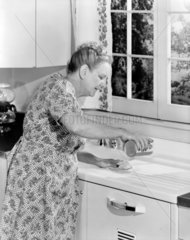 Woman cleaning a kitchen sink  1955.