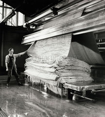 A Kossett millworker at machine tends a pile of carpet after dying  1956.