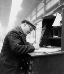 Clerk at a goods depot entering details in a ledger.