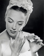 Woman applying skin cream  1945-1955.