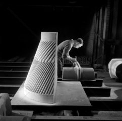 A sand core before moulding  a recently cast fluted liner core in foreground.