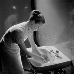Young woman washing hands in washroom  Cheltenham  1957.