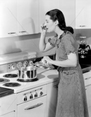 Woman tasting her cooking  c 1955.