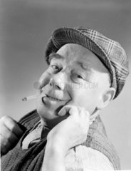Portrait of a man in a flat cap smoking a cigarette  1949.