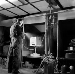A painter sprays a16mm projector case  Mitcheldean 1956.