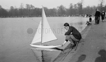 Man releasing a model boat onto a pond c.1930s.