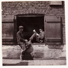 Two boys sitting on a window ledge  c 1905.